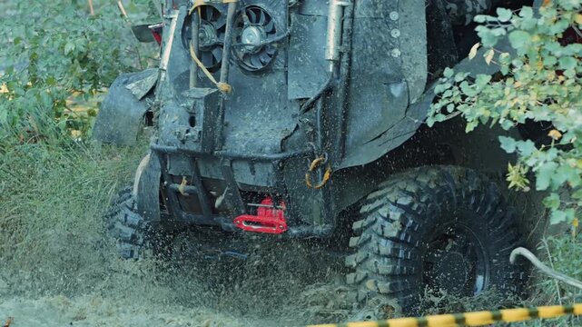 Close up action shot of rugged off road truck splashing through murky water during extreme sports competition. Powerful 4x4 vehicle creates huge mud splash. Thrilling, adventurous outdoor event