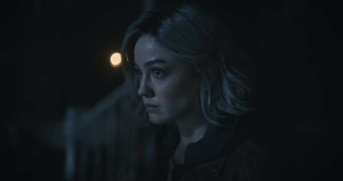 Young, cautious woman looking around with flashlight and tilting down to notebook - closeup shot