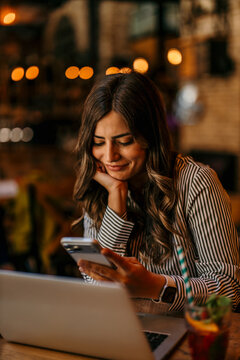 Woman looking at smartphone smiling at cafe