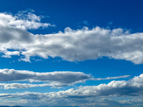 Layered cumulus clouds over blue sky above Vouliagmeni coast in Attica Greece on autumn afternoon