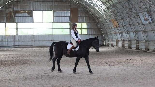 Woman riding horse in indoor equestrian arena