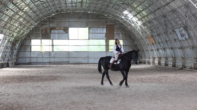 Woman riding horse in indoor equestrian arena