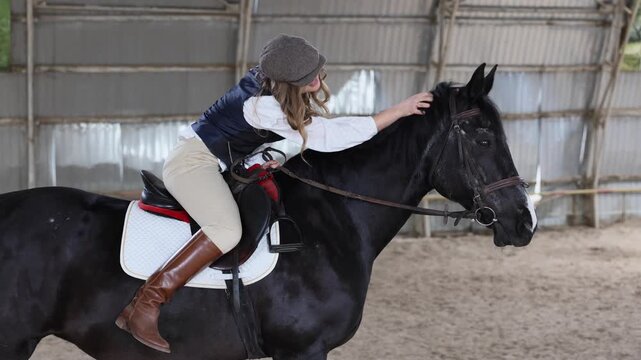 Woman riding horse in indoor equestrian arena