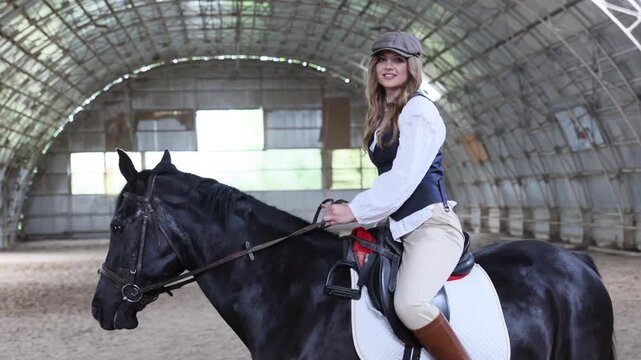 Woman riding horse in indoor equestrian arena