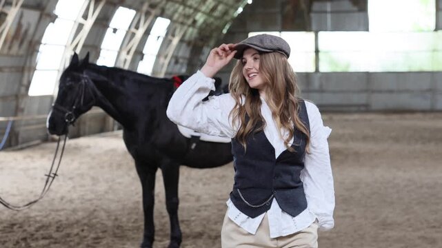 Woman with flat cap and black horse in riding arena