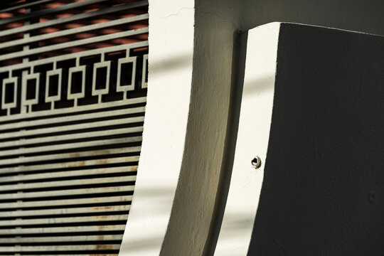 Graphic urban facade in curved stucco shadow with metal grille pattern
