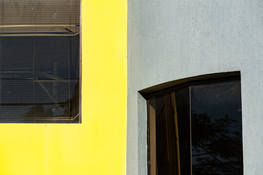 Graphic yellow and blue facade frames dark window reflections in urban exterior