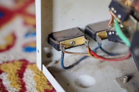 Internal electrical wiring and switch terminals inside a dirty metal casing of a stavolt stabilizer.