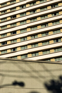 Repeating hotel window pattern rises above foreground wall and soft street shadow