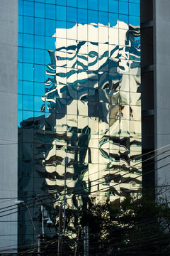Distorted building reflection ripples across mirrored blue glass facade