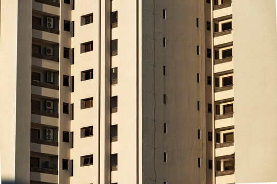 Beige residential facades align narrow windows and recessed balconies in repetition