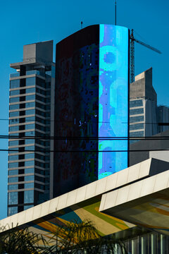 Digital cylindrical facade rises between modern towers above diagonal foreground