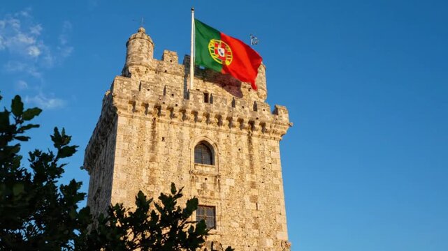 The historic belm tower in lisbon, portugal, flying the national flag against a clear blue sky