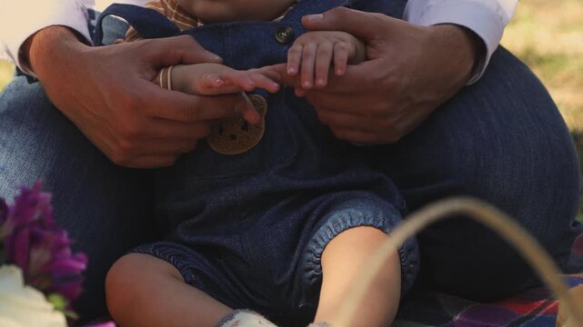 Cute baby being lifted by father during a relaxing family outing surrounded by trees and fresh air.