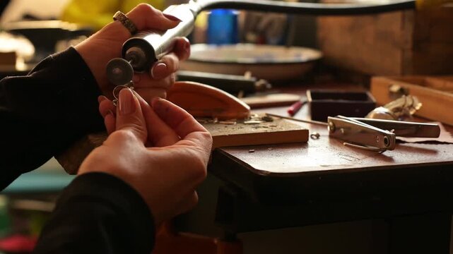 4k video with zoom in of a female jewelry artisan sanding a silver ring with her Dremel
