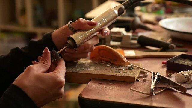 4k video of a female jewelry artisan sanding a silver ring with her Dremel
