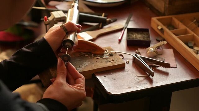 4k video of a female jewelry artisan sanding a silver ring with her Dremel
