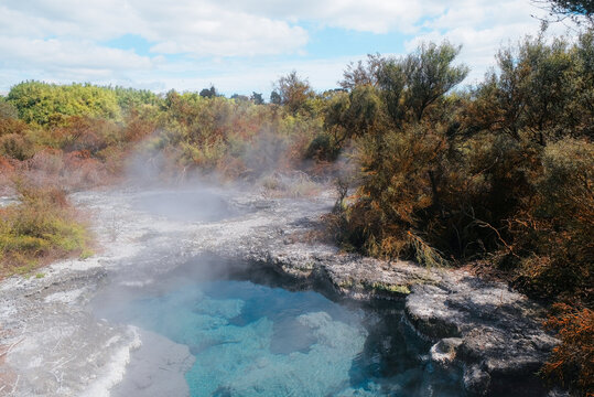 Rotorua, New Zealand: Vibrant blue geothermal hot spring pool with volcanic steam and white silica mineral crust margins at Te Puia thermal valley.