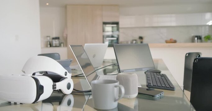 Camera is moving forward across glass dining table, drawing laptops, mugs and VR headset into focus