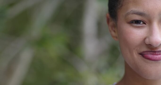 African American woman posing right in park smiling reacting to camera hair pulled back, copy space