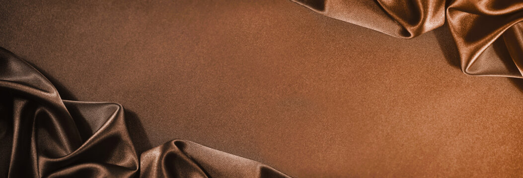Black dark chocolate coffee copper brown silk satin. Shiny silky smooth fabric. Soft folds. Draped. Elegant luxury background. Empty blank template design ad. Wide banner. Flat lay, table top view.