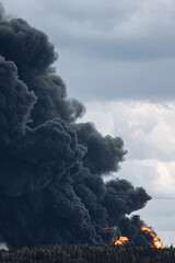 Fototapeta premium Black smoke billowing from a landfill fire, showing dangerous atmospheric pollution and global ecological crisis caused by improper waste disposal and burning tires