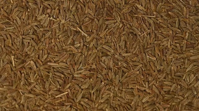 Top view macro shot of a heap of raw organic cumin seeds rotating slowly. Premium aromatic spice texture background
