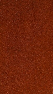 Top view macro shot of fine ground red paprika spice rotating slowly. Premium hot chili or sweet pepper powder texture background