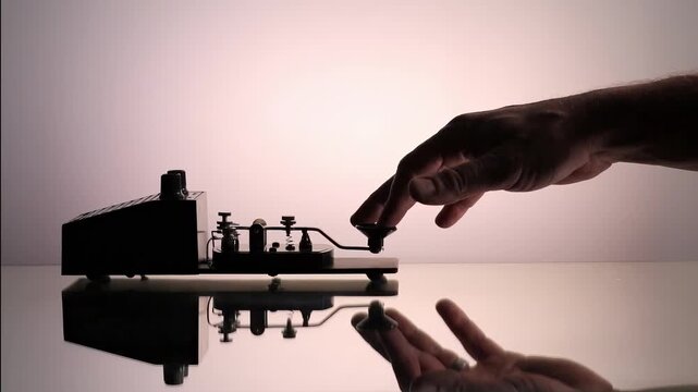 Hand operating vintage Morse code telegraph key sending messages with reflection