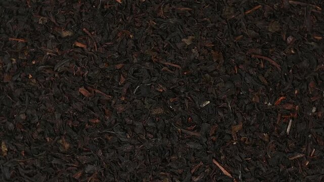 Macro top view shot of loose dried black tea leaves rotating slowly. Premium loose-leaf tea texture background.