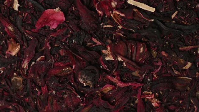 Top view macro shot of loose dried hibiscus flowers rotating slowly. Premium red karkadeh herbal tea texture background