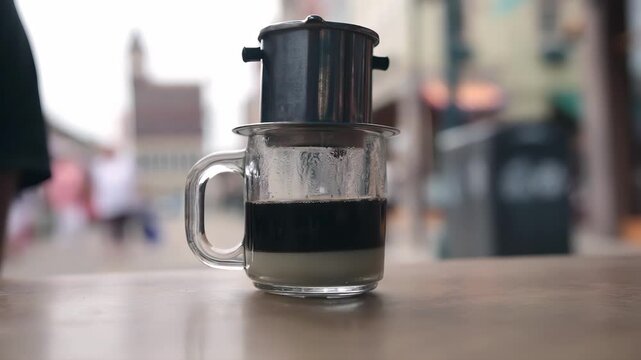 Brewing Vietnamese coffee with condensed milk in a glass mug outdoors