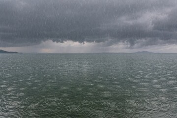 Fototapeta premium 暗い雷雲の下で湖面へ降り注ぐ夏の激しい雨