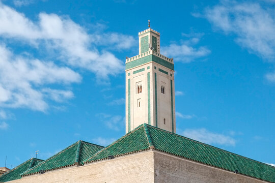 Green tiled minaret against a bright blue sky