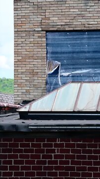  rundown building rooftop showing blue tarp waving in the wind