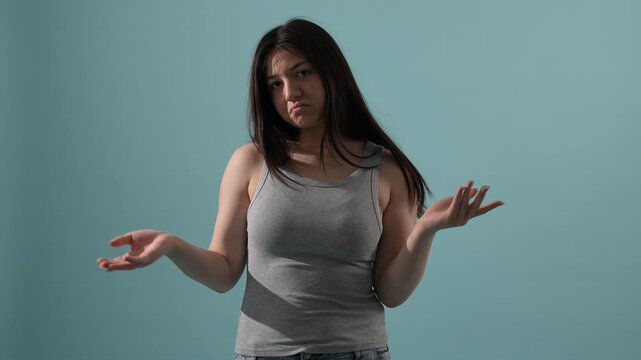 Confused young woman shrugging shoulders and doubting her choice