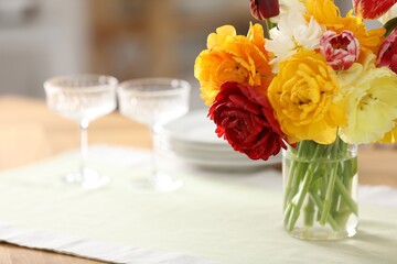 Obraz premium Beautiful tulips in vase on wooden table in kitchen, closeup. Space for text