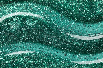 Green glitter nail polish as background, top view