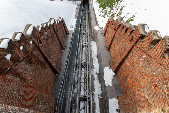 Snowcovered Brick Towers And Narrow Alley Converging Toward Distant Vanishing Point, Frozen Parapets Dusted With Snow, Worn Masonry Revealing