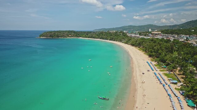 Karon beach tropical paradise with turquoise water, long sandy coastline, green palm trees, distant buildings, perfect destination for vacation and tourism. Phuket island. Aerial view drone flight
