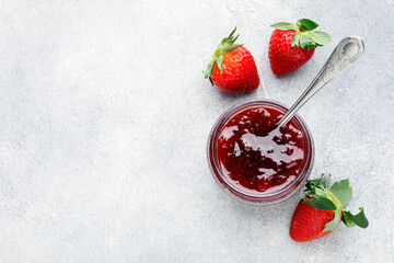 Fototapeta premium Tasty strawberry jam in jar and fresh berries on light grey table, flat lay. Space for text