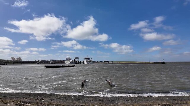 Maritime scene capturing the ferry departing from Lauwersoog harbour, reversing slowly to begin the crossing to the Wadden island of Schiermonnikoog. The sunny weather bathes the scene in warm light