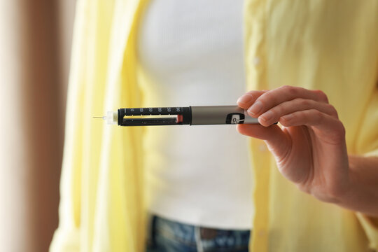 Diabetes. Woman with autoinjector at home, closeup