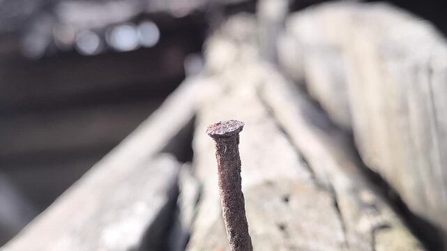 A close-up of a rusty nail against a backdrop of ruins. The concept of unbreakability.
