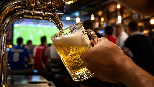 Bartender pouring draft beer in pub full of soccer fans
