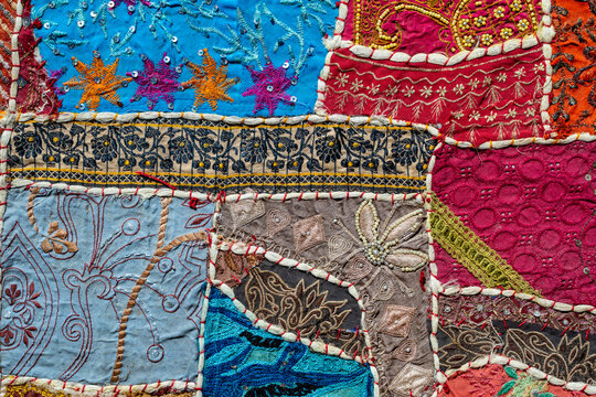 Indian handmade patchwork fabric texture with colorful embroidery and sequins. Background traditional vintage rajasthani patchwork quilt with colorful embroidery beads and sequins decoration