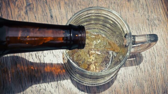 Top Down View of Cold Beer Pouring into Glass Mug with Frothy Foam
