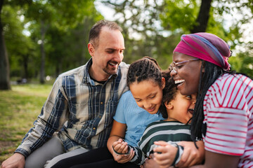 Fototapeta premium Multiracial family laughing together experiencing happiness in park