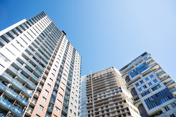 Fototapeta premium Urban high-rise buildings with a central unfinished tower in bright daylight