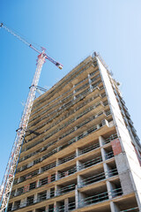 Fototapeta premium High-rise building under construction with tower crane, urban development and real estate concept